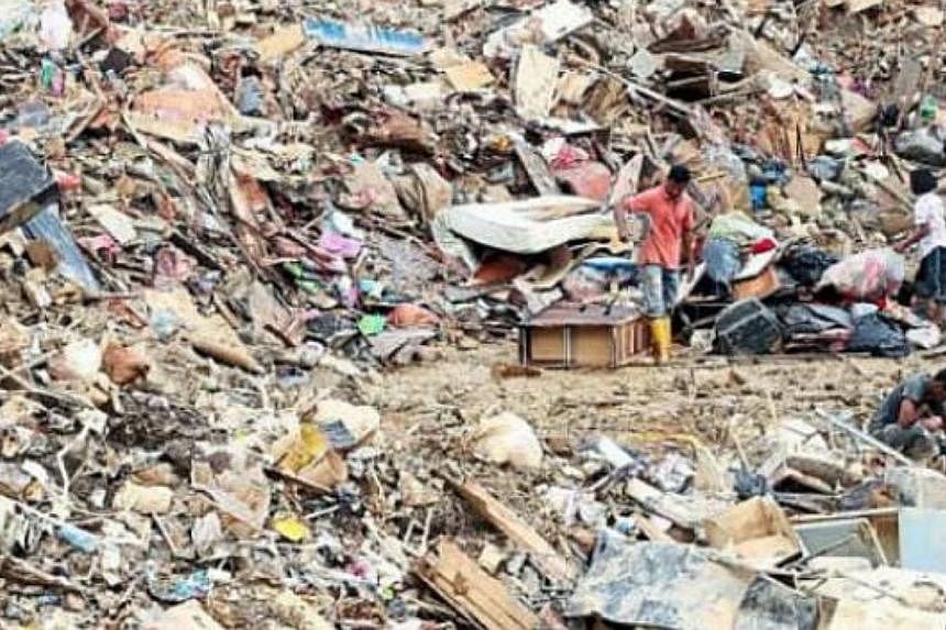 Villagers salvaging useful items from flood trash at an unregistered disposal site in Kuala Krai, Kelantan. -- PHOTO: THE STAR/ASIA NEWS NETWORK
