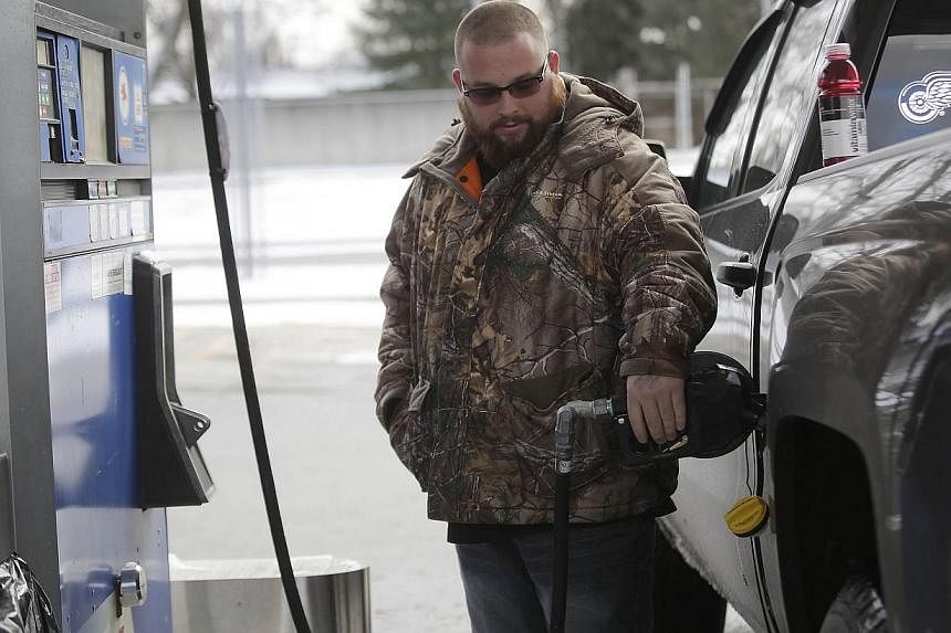 A motorist filling his vehicle with fuel at a Mobil station on Jan 6, 2015 in Livonia, Michigan, in the US. The oil price plunge will force energy companies to slash capital spending in North America, Europe and Asia in 2015, while investment continu