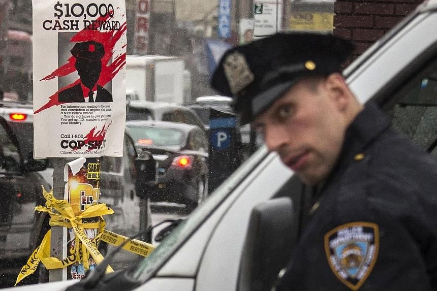 A New York Police Department officer standing next to a sign posted near the site of a shooting in the Bronx borough of New York on Jan 6, 2015. Three people have been arrested for the shooting of two plainclothes officers in the area. -- PHOTO: REUT