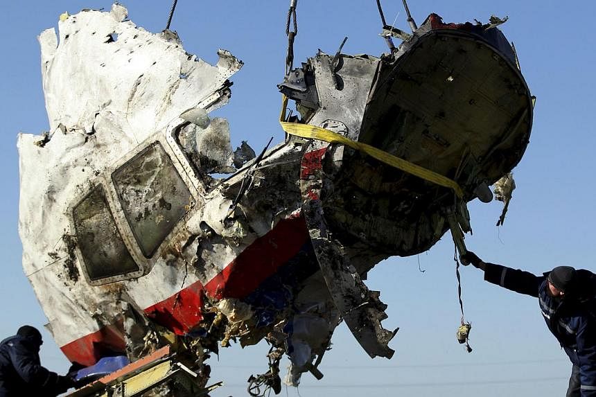 Local workers transport a piece of the Malaysia Airlines flight MH17 wreckage at the site of the plane crash near the village of Hrabove (Grabovo) in the Donetsk region, eastern Ukraine Nov 20, 2014. -- PHOTO: REUTERS