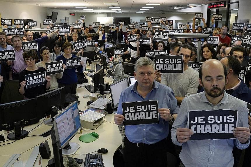 Journalists with placards reading "I am Charlie" observing a minute of silence, on Jan 7, 2015, following the attack by gunmen in the offices of the French satirical weekly Charlie Hebdo. -- PHOTO: AFP