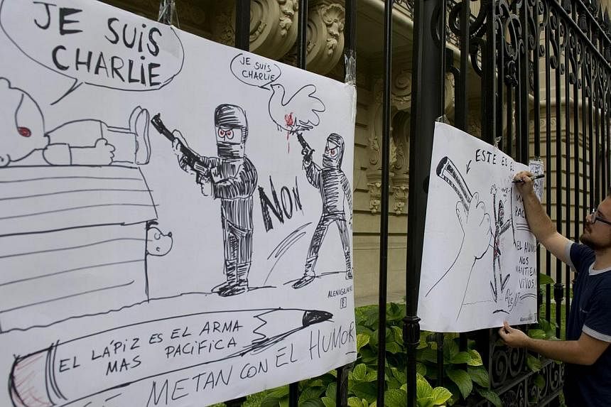 An Argentine cartoonist drawing at the gates of the French Embassy in Buenos Aires on Jan 7, 2015, during a demonstration against the attack on the satirical weekly Charlie Hebdo in Paris. -- PHOTO: AFP