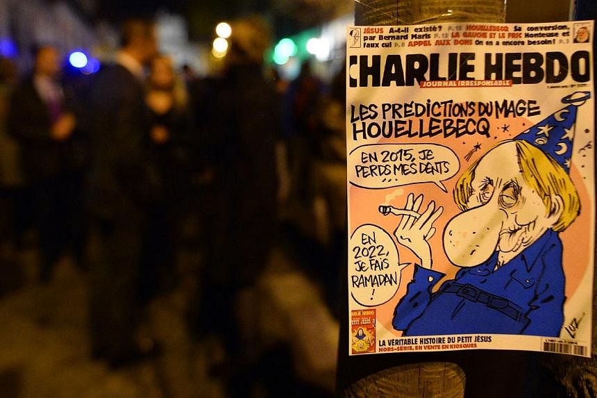 The frontpage of last issue of French satirical newspaper Charlie Hebdo is seen during a gathering in support of the victims of the terrorist attack on its Paris offices, in front of the French Embassy in Madrid, on Jan 7, 2015. -- PHOTO: AFP