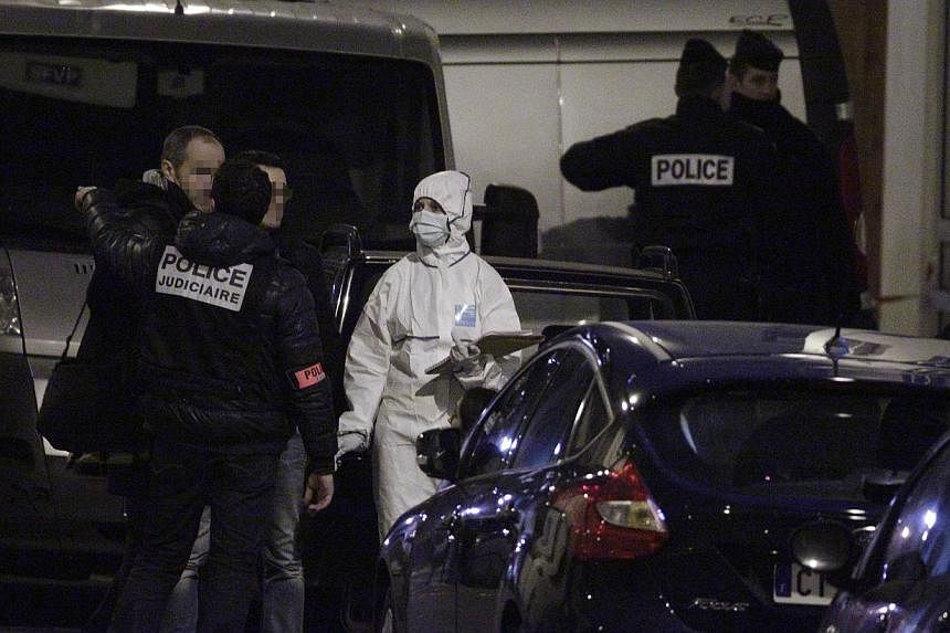 French police and forensic investigators stand outside the offices of French satirical weekly Charlie Hebdo after armed gunmen stormed the offices on Jan 7, 2015. -- PHOTO: AFP&nbsp;