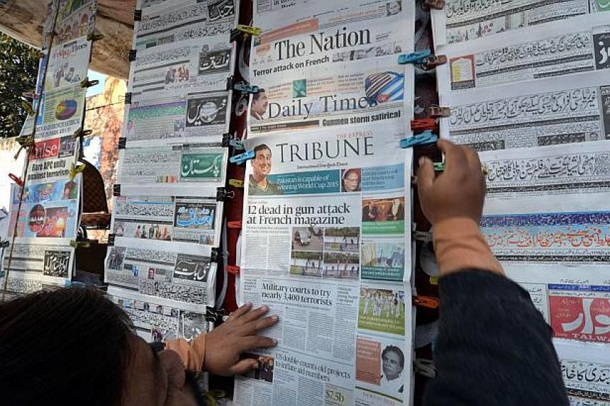 A Pakistani vendor arranging morning newspapers with front-page-coverage of the attack by gunmen on French satirical weekly Charlie Hebdo in Paris, at a roadside newsstand in Islamabad on Jan 8, 2015. -- PHOTO: AFP
