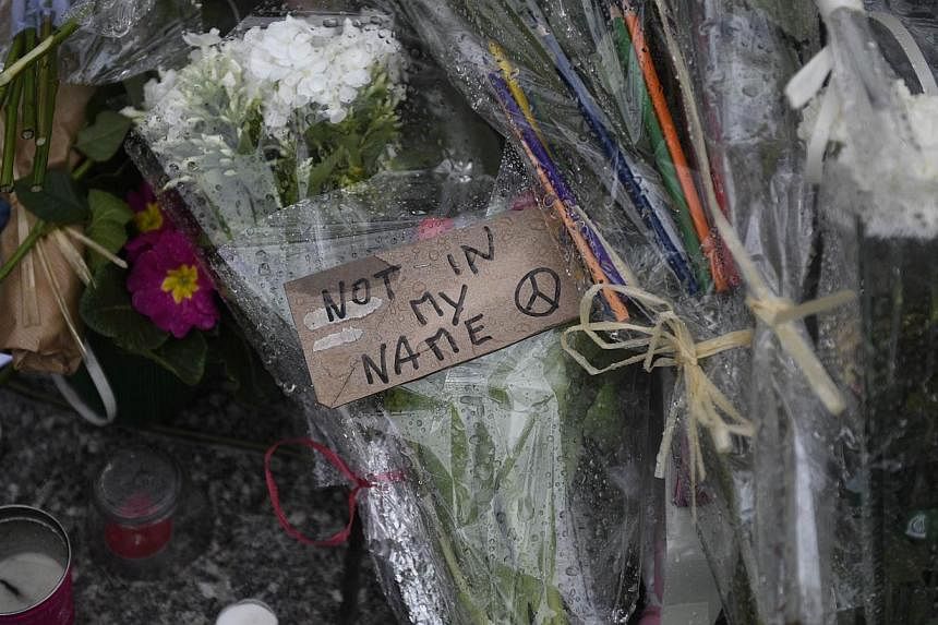 Floral tributes are laid on the ground during a minute of silence outside the offices of the French satirical magazine Charlie Hebdo in Paris on Jan 8, 2015.&nbsp;Outside the blood-stained offices of Charlie Hebdo, crowds left tributes Thursday to th