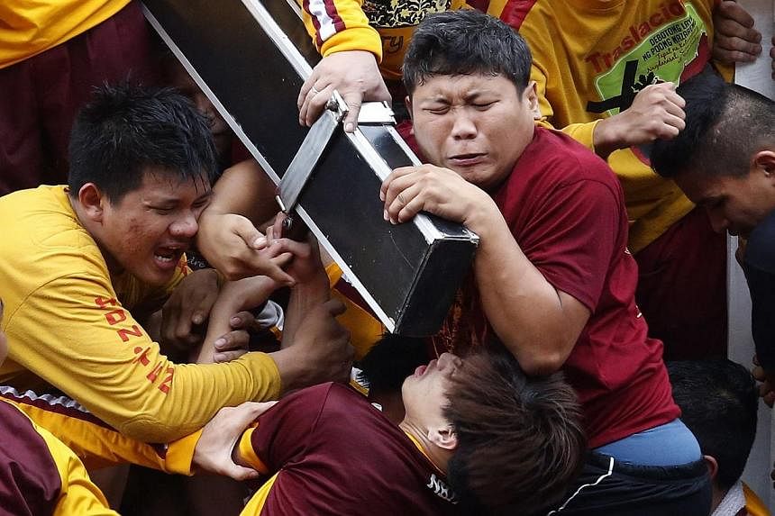 Devotees grimace as they try to hold the Black Nazarene, which is atop a carriage, at the start of an annual procession in Manila, Jan 9, 2015.&nbsp;-- PHOTO: REUTERS