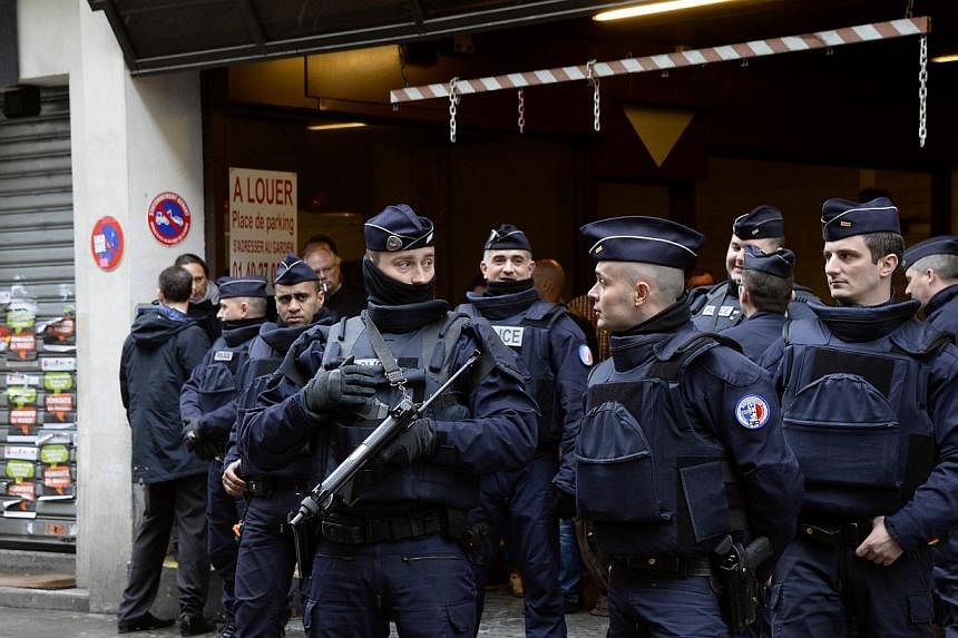 French police officers stand guard in front of the headquarters of French newspaper Liberation as editorial staff of French satirical weekly newspaper Charlie Hebdo and Liberation meet, on Jan 9, 2015, in Paris, after a deadly attack that occurred on