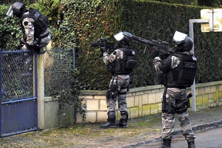 Members of the GIPN, a French police special forces, walk in Corcy, northern France, on Jan 8, 2015 carry out searches as part of an investigation into a deadly attack the day before by armed gunmen on the Paris offices of French satirical weekly Cha
