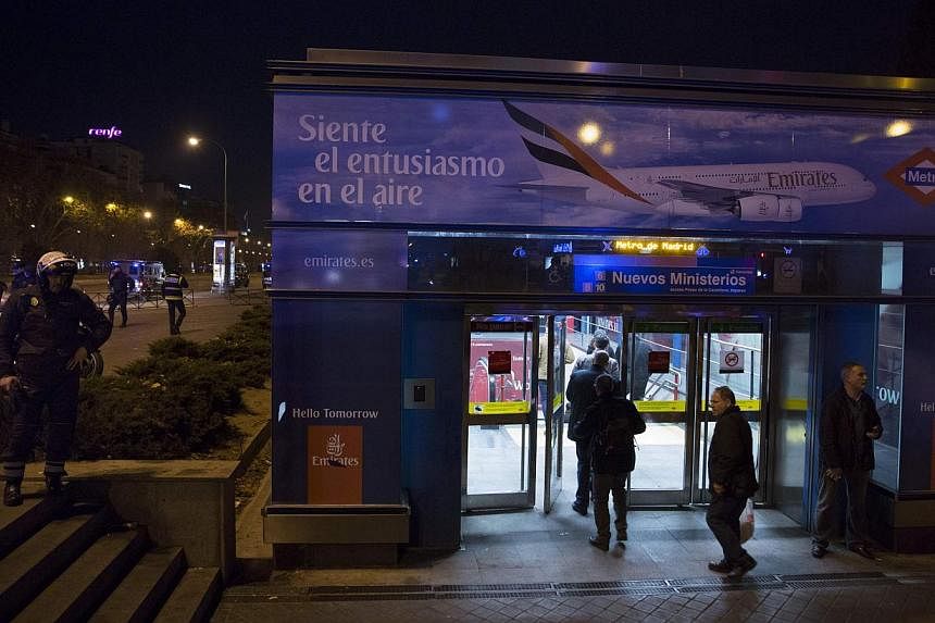People enter Nuevos Ministerios station as a policeman watches in Madrid Jan 8, 2015. A suspicious package at Madrid's Nuevos Ministerios train station did not contain anything dangerous, a Madrid government official and police said on Thursday. -- P
