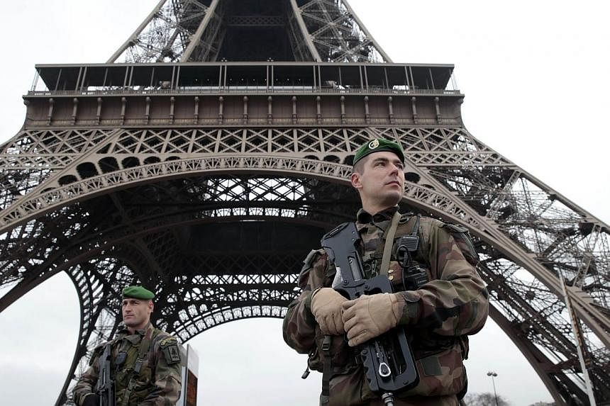 French soldiers patrol in front of the Eiffel Tower on Jan 7, 2015 in Paris.&nbsp;France's iconic Eiffel Tower is to go dark late on Thursday in a sombre tribute to the 12 people killed in the attack on the Paris satirical newspaper Charlie Hebdo. --