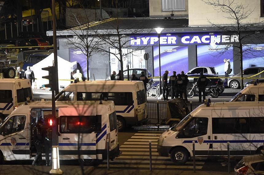 Forensic police (left) work outside the Hyper Casher kosher grocery store near Porte de Vincennes, eastern Paris, on Jan 9, 2015, after police launched an assault killing the gunman holed up in the market and freeing the hostages. -- PHOTO: AFP