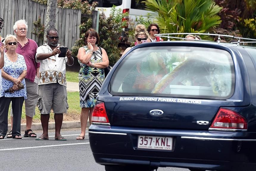 Local residents line the road as a hearse carrying one of the coffins of the eight children in Cairns, Australia, on Jan 10, 2015. -- &nbsp;PHOTO: EPA
