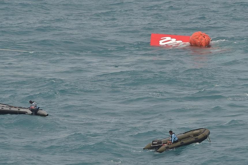 Part of the tail of AirAsia flight QZ8501 floating on the water's surface as Indonesian Navy divers conduct search operations for black boxes of the aircraft in the Java sea on Jan 10, 2015. -- PHOTO: AFP