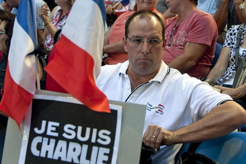 A spectator at the Hopman Cup tennis tournament in Perth, Australia, on Jan 9, 2015, holding French flags and a placard saying "Je Suis Charlie". France's Alize Cornet was playing against Poland's Agnieszka Radwanska. -- PHOTO: AFP