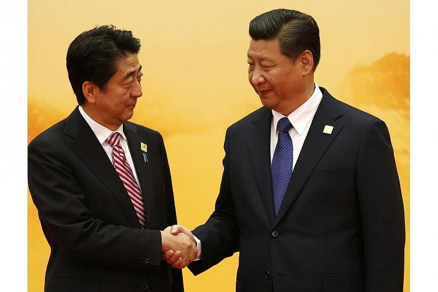 Japan's Prime Minister Shinzo Abe (left) shakes hands with China's President Xi Jinping during the welcoming ceremony at the Asia Pacific Economic Cooperation (APEC) forum, inside the International Convention Center at Yanqi Lake, in Beijing, on Nov 