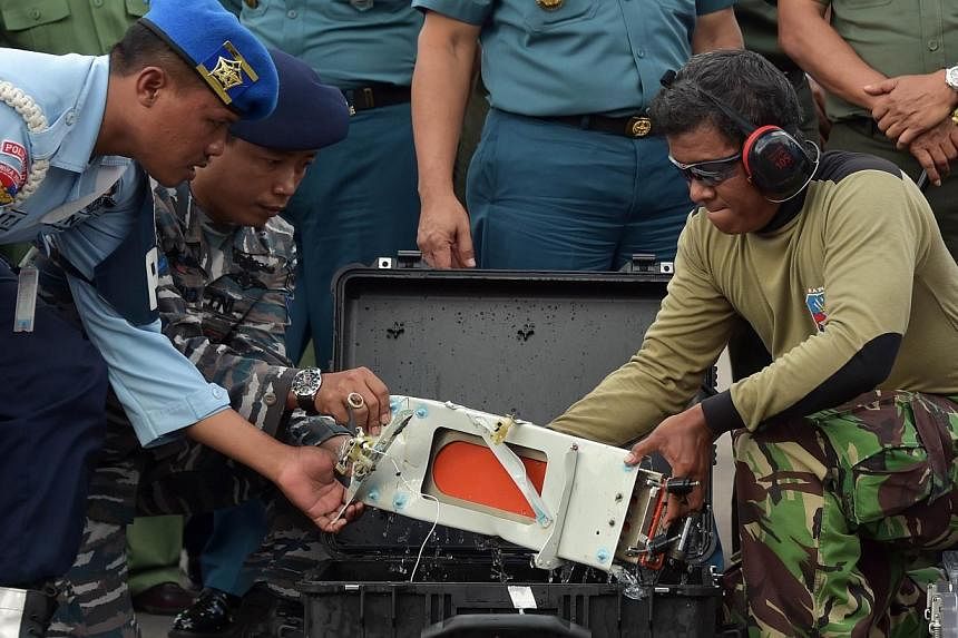 Indonesian officers move the FDR (Flight Data Recorder) of AirAsia flight QZ8501 into a suitable protective transportation case in Pangkalan Bun after it was retrieved from the Java Sea on Jan 12, 2015.&nbsp;-- PHOTO: AFP