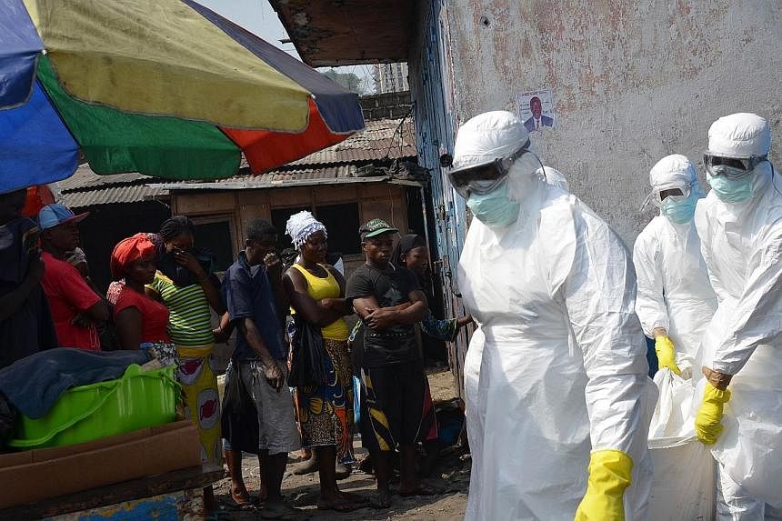 Red cross workers, wearing protective suits, carry the body of a person who died from Ebola during a burial with relatives of the victims of the virus, in Monrovia, on Jan 5, 2015.&nbsp;China has been quietly toughening travel restrictions on student