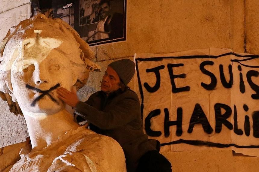 A man touching the mouth of a statue that had been spray-painted shut near a poster reading "I am Charlie" as he takes part in a solidarity march (Marche Republicaine) in the streets of Paris on Jan 11, 2015.&nbsp;Blanket news coverage around the wor