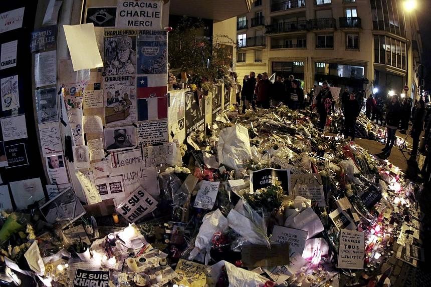 People visit a makeshift memorial near the headquarters of the French satirical weekly Charlie Hebdo at the end of the unity rally "Marche Republicaine" on Jan 11, 2015 in Paris. A veteran Algerian militant and former Al-Qaeda fighter, Mokhtar Belmok