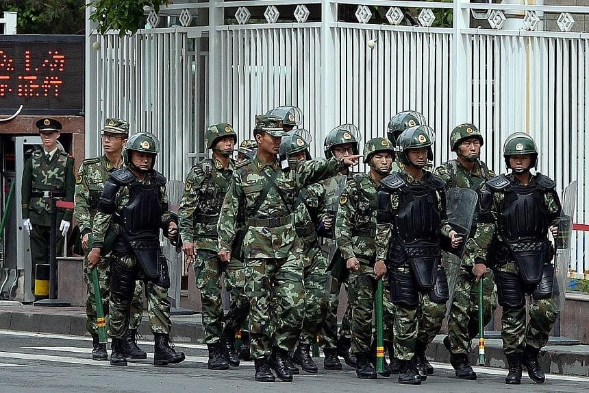 This file picture taken on on May 23, 2014 shows fully armed Chinese paramilitary police patrol a street in Urumqi, the capital of farwest China's Muslim Uighur homeland of Xinjiang. -- PHOTO: AFP