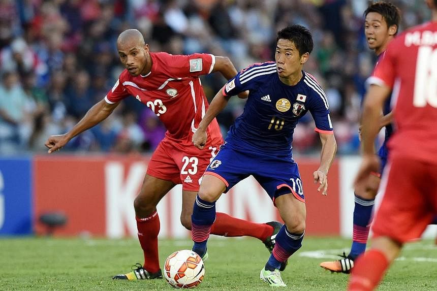 Shinji Kagawa of Japan, (right), is challenged by Murad Said of Palestine during the Group D Asian Cup match at Newcastle Stadium in Newcastle, Australia, on Jan 12, 2015.&nbsp;Japan kicked off their Asian Cup title defence with a 4-0 victory over As