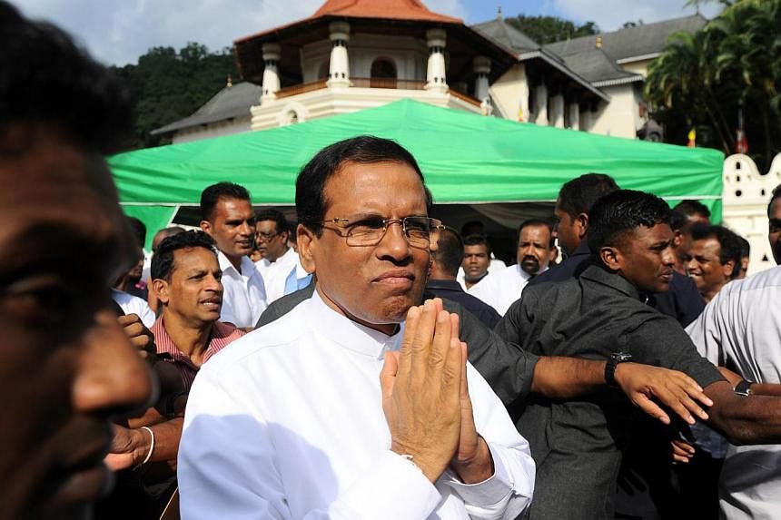 New Sri Lankan President Maithripala Sirisena gestures to supporters after speaking outside of the Buddhist Temple of Tooth in the central town of Kandy on Jan 11, 2015.&nbsp;Sri Lanka's new president has axed hundreds of officials and diplomats appo