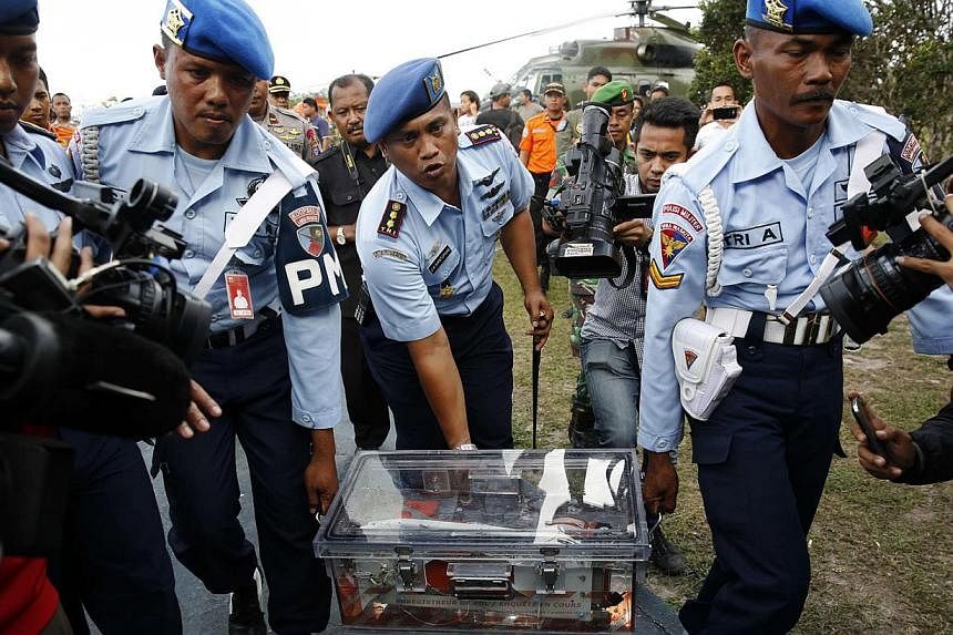 Military policemen carry the flight data recorder of AirAsia flight QZ8501 at the airbase in Pangkalan Bun, Central Kalimantan on Jan 12, 2015. Indonesian navy divers on Monday retrieved it from the plane that crashed two weeks ago, killing all 162 p