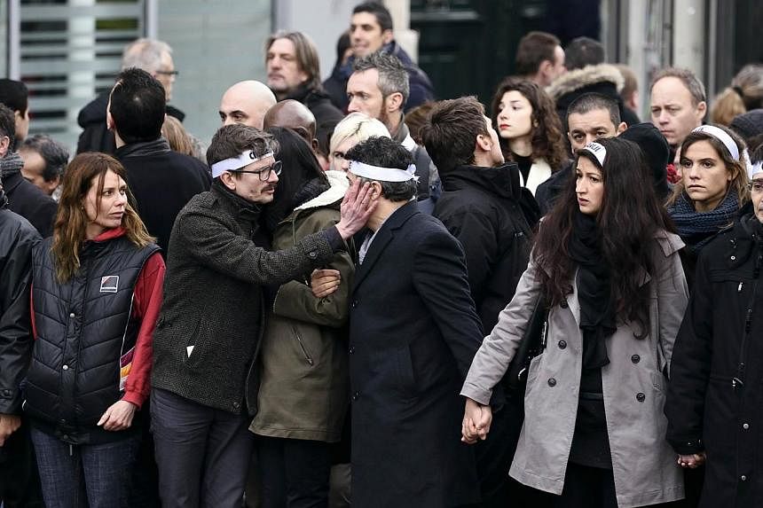 Members of the Charlie Hebdo satirical magazine looking on as Luz (third from left) touches the cheek of Dr Patrice Pelloux at the “Marche Republicaine”. -- PHOTO: AFP