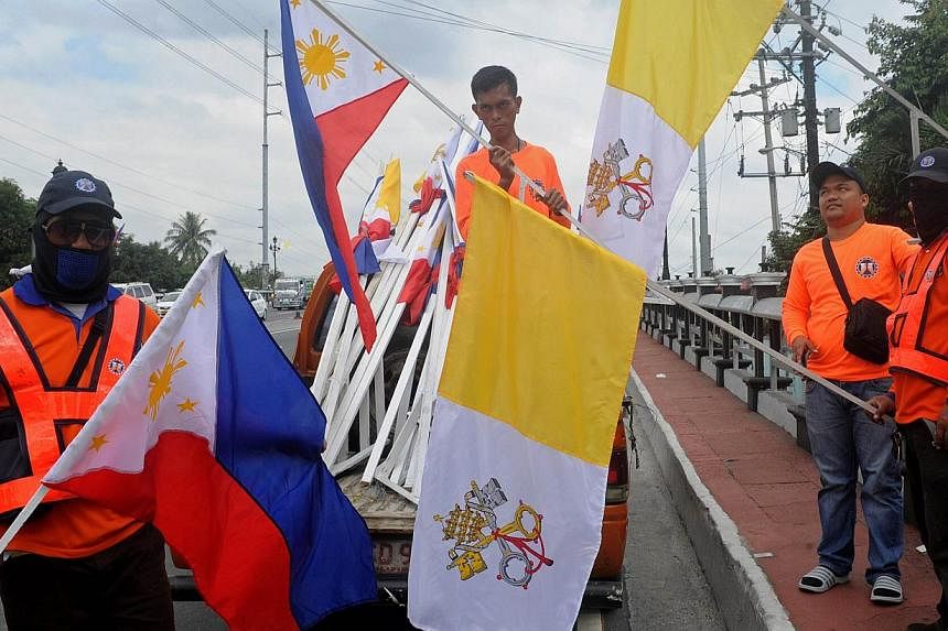 Workers install Philippine and Vatican flags ahead of a visit by Pope Francis in Manila, on Jan 11, 2015. The Pope will immerse himself in some of Asia's most fervent Catholicism during a trip to Sri Lanka and the Philippines starting on Tuesday, wit