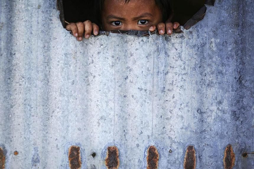 A child peers from inside a makeshift house with tin walls Jan 15, 2015, in the coastal part of Tacloban that was destroyed by Typhoon Haiyan. On his first visit to Asia's largest Catholic nation, Pope Francis will visit the central province of Leyte