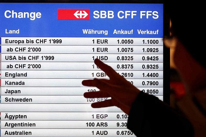 A man looking in Bern, Switzerland, at a board showing currency exchange rates on Jan 15, 2015. The Swiss National Bank shocked financial markets on Thursday by scrapping a three-year-old cap on the Swiss franc, sending the safe-haven currency soarin