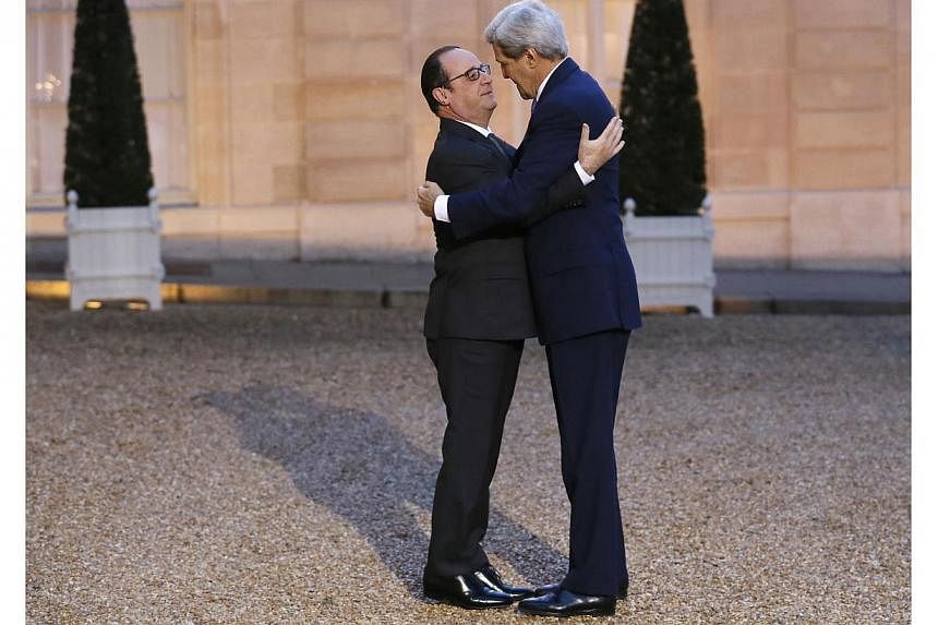 French president François Hollande (left) embraces US Secretary of State John Kerry prior to a meeting at the Elysee Palace on Jan 16, 2015, in Paris. -- PHOTO: AFP
