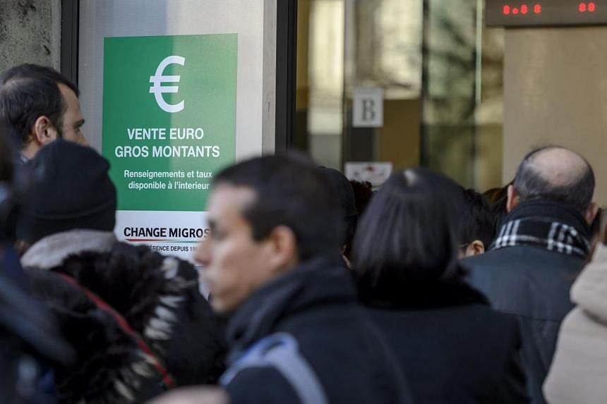 People queue at a bureau de change in Geneva on Jan 15, 2015, after Switzerland's central bank scrapped a policy to artificially hold down the value of the Swiss franc against the euro, sending the franc soaring. Following the announcement, the Swiss