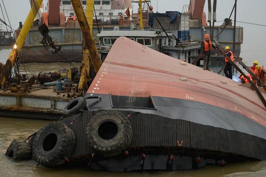 Members of a rescue team (orange) look at a section of the hull (front) of a tugboat which sank on a trial voyage in Jingjiang, east China's Jiangsu province, on Jan 16, 2015.&nbsp;Three of the people on board the tugboat that sank in China's Yangtze
