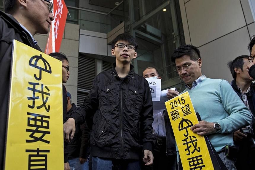 Student leader Joshua Wong (centre) being surrounded by supporters as he arrives at the police headquarters in Hong Kong on Jan 16, 2015. -- PHOTO: REUTERS