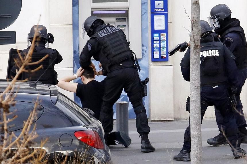 A man (kneeling), who had taken two hostages in a post office, is arrested by French Research and Intervention Brigades (BRI) police officers on Jan 16, 2015, in Colombes, outside Paris.&nbsp;-- PHOTO: AFP