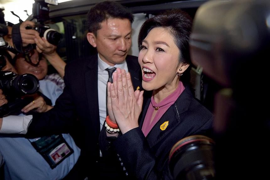 Ousted Thai prime minister Yingluck Shinawatra (centre) gestures a traditional greeting to members of the media in Bangkok on Jan 9, 2015. The&nbsp;Former Thai Prime Minister failed to appear at her second impeachment hearing on Friday, sending minis