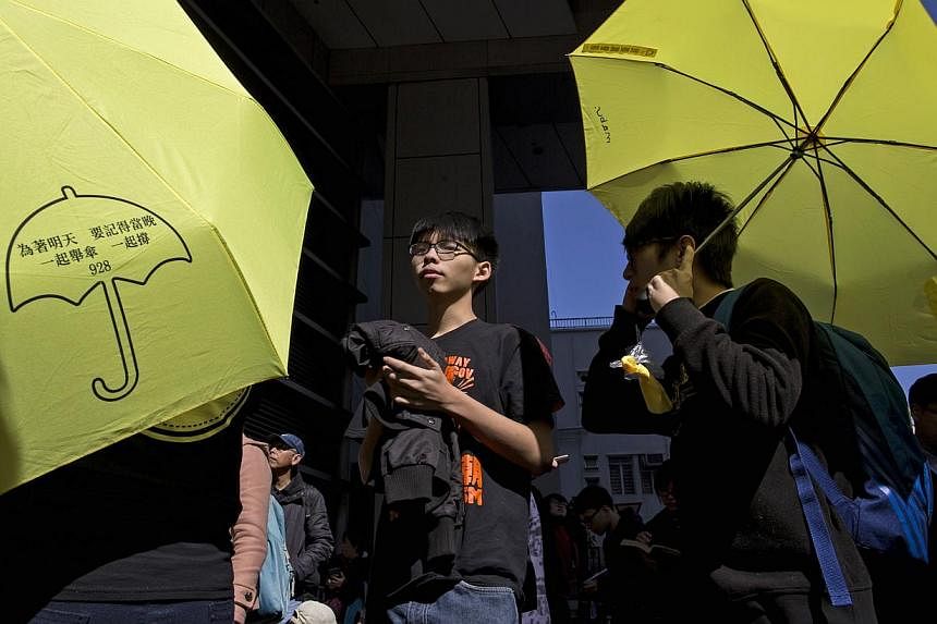Hong Kong student leader Joshua Wong (centre), 18, is surrounded by supporters holding yellow umbrellas as he arrives at the police headquarters in Hong Kong on Jan 16, 2015. -- PHOTO: REUTERS