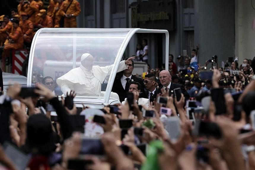 Pope Francis (centre), riding on a 'Popemobile', waves to Filipino well wishers at a street to lead a mass at the Manila cathedral, in Manila, Philippines on Jan 16, 2015. -- PHOTO: EPA