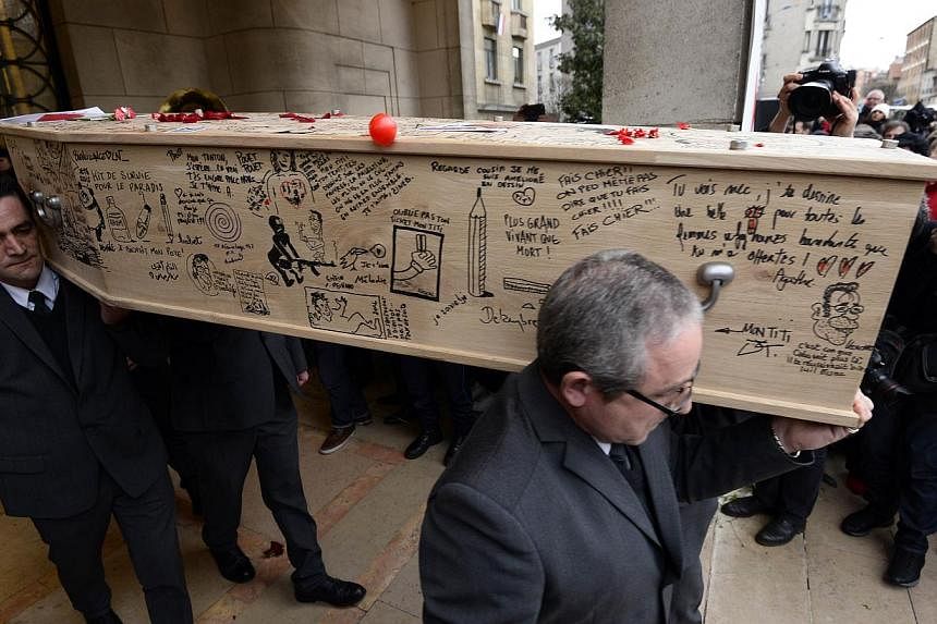 The coffin of cartoonist Bernard "Tignous" Verlhac, 57, one of the 12 people killed in the Jan 7 attack on French satirical weekly Charlie Hebdo, being carried out of the town hall of Montreuil, near Paris, during his funeral on Jan 15, 2015. -- PHOT