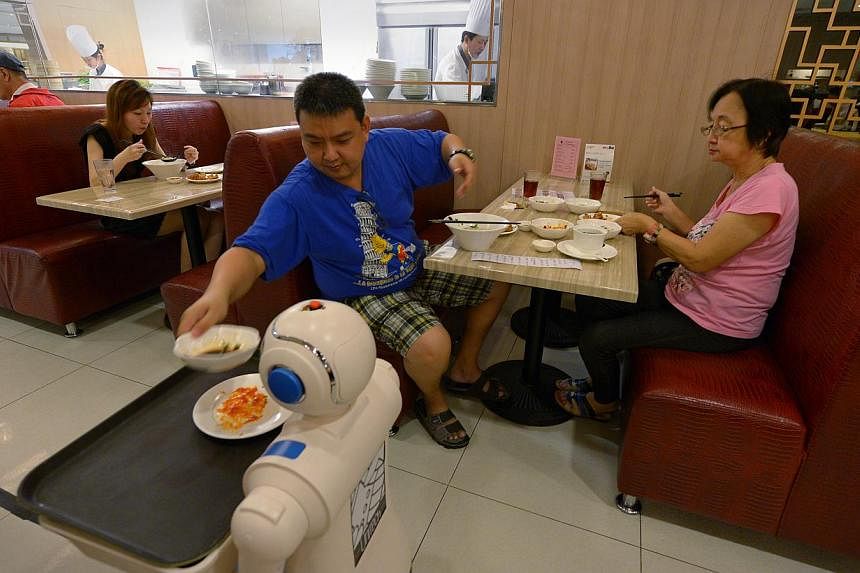 A robot is used by Jiang Nan restaurant at Marina Square to help clear used dishes. The intent behind productivity-centric schemes is to be lauded but moving the needle from policy to effective implementation looks to be the real challenge, say two w