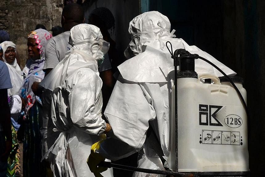 Red cross workers, wearing protective suits, get ready during a burial for victims of the virus, in Monrovia, on Jan 5, 2015. -- PHOTO: AFP