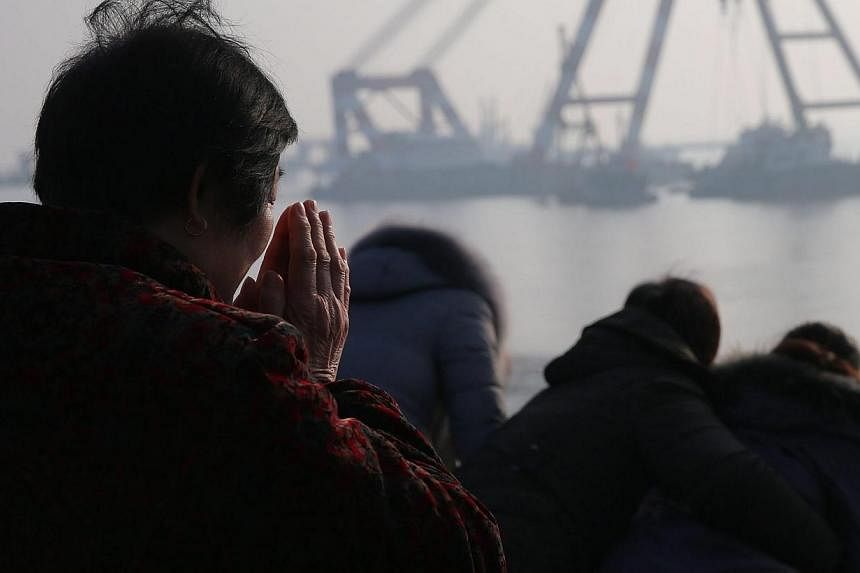 A relative prays on the river bank during search and rescue operations on an overturned tugboat in the Yangtze River, Jingjiang city, Jiangsu province, China, on Jan 17 2015. -- PHOTO: EPA