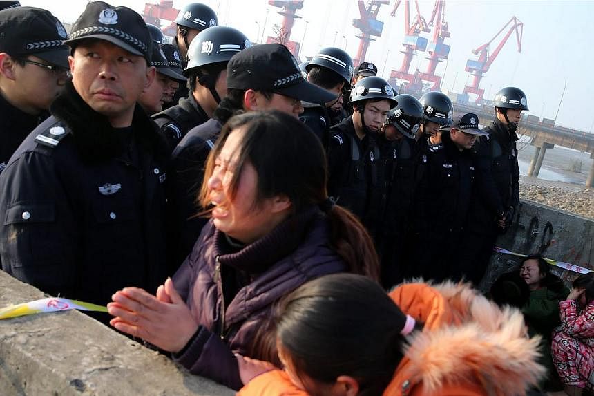 Relatives of missing persons react next to police officers on the river bank during search and rescue operations on an overturned tugboat in the Yangtze River, Jingjiang city, Jiangsu province, China on Jan 17, 2015. -- PHOTO: EPA