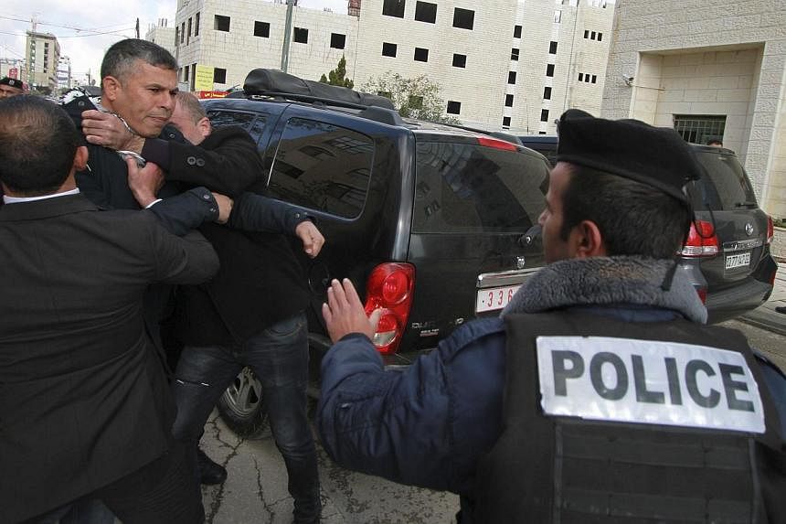Members of Palestinian security forces and a policeman hold back a protester after eggs were thrown at Canada's Foreign Minister John Baird, during his visit to the West Bank city of Ramallah on Jan 18, 2015.&nbsp;Palestinian protesters heckled and t