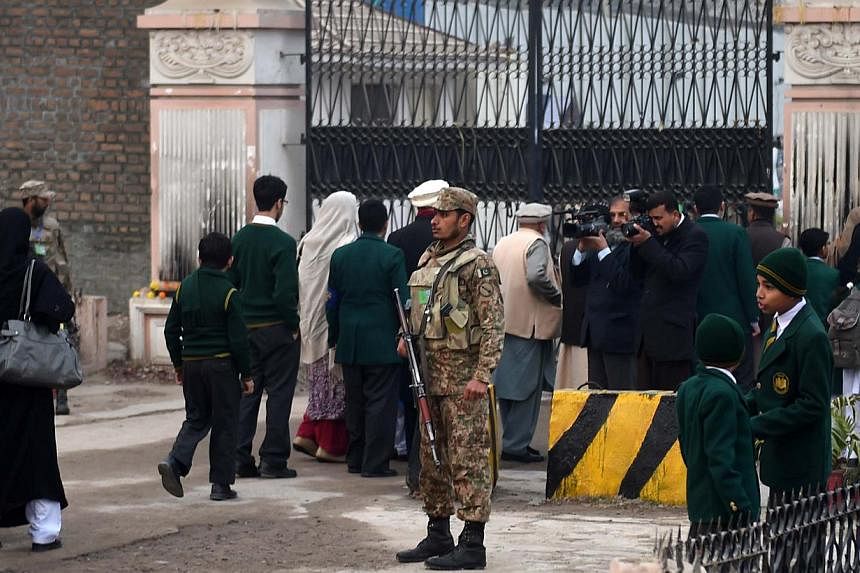 Pakistani soldiers stand guard as parents arrive with their children at the Army Public School in Peshawar on Jan 12, 2015.&nbsp;Five Pakistani men have been arrested in Afghanistan in connection with the Taleban massacre of 134 school children at th