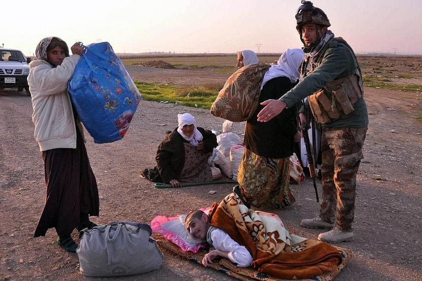 A Kurdish peshmerga fighter helps a Yazidi family after they were freed by Islamic State in Iraq and Syria militants, south-west of the northern Iraqi city of Kirkuk on Jan 17, 2015. ISIS group fighters have freed more than 200 captive members of Ira