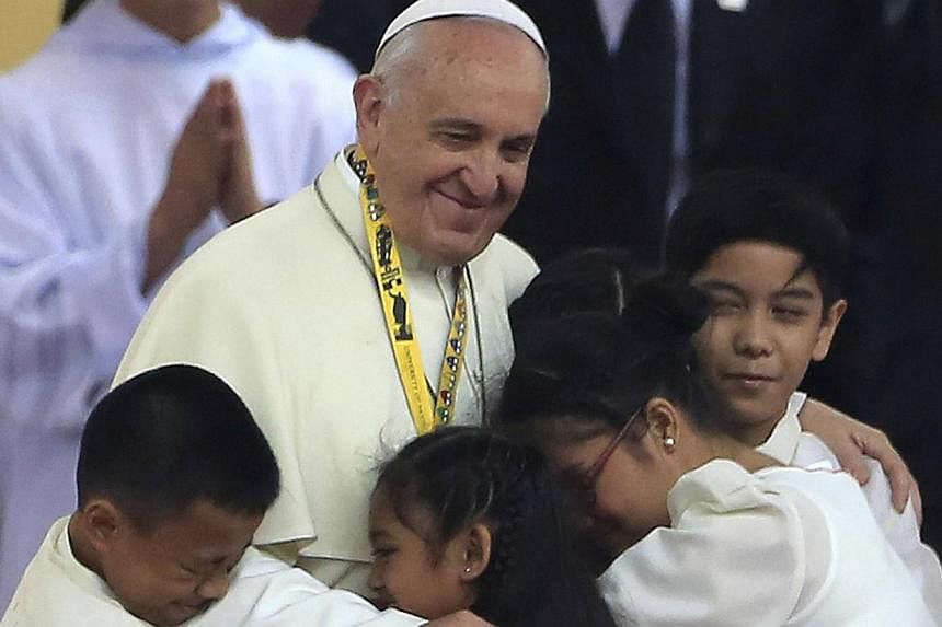 Pope Francis huggin children during a meeting with young people at the University of Santo Tomas in Manila on Jan 18, 2015. An emotional Pope Francis, moved by the tears of an abandoned child, said on Sunday the world needed to "learn how to cry" ove