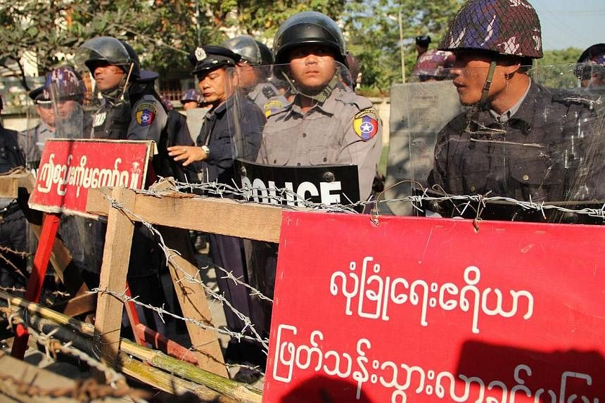 Police stand guard next to a barricade as protesters (not seen) demand the closure of a flashpoint copper mine as they gather near the Chinese consulate in Myanmar's central city of Mandalay on Dec 27, 2014. -- PHOTO: AFP